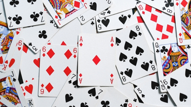Deck of casino playing cards scattered around on flat surface.