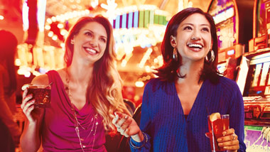 two women with drinks at slot machines