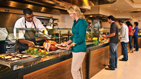 people at L'Auberge's Bon Temps Buffet line, focusing on woman and chef carving ham